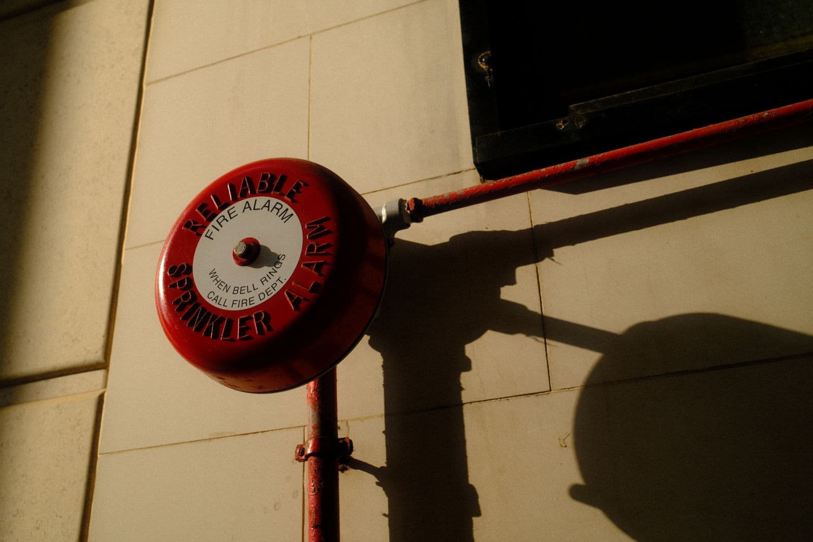 Red fire alarm bell mounted on a commercial building exterior